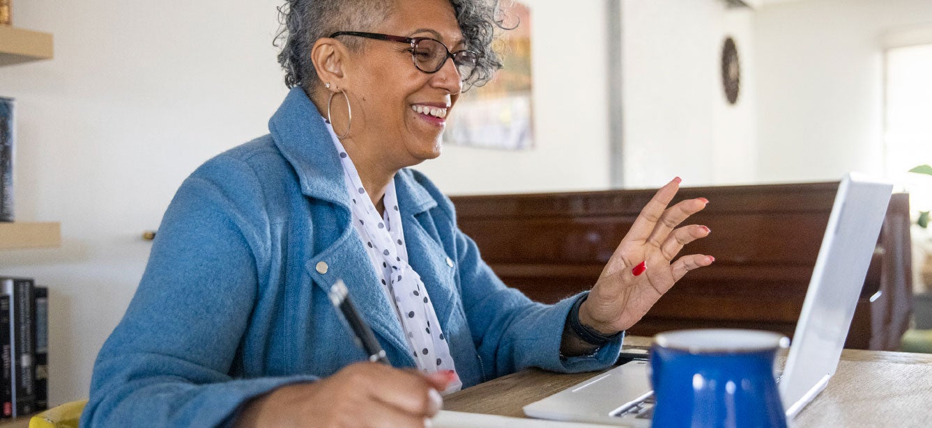 Older woman smiling while using a laptop with growing confidence